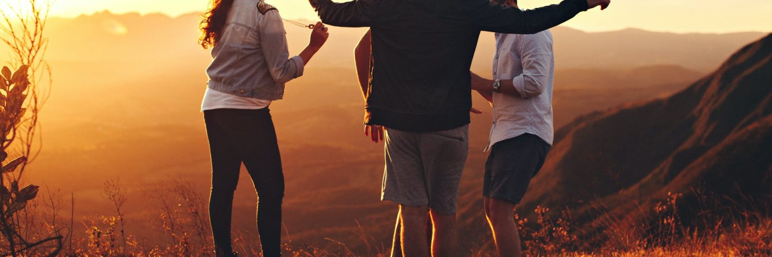 four person standing at top of grassy mountain