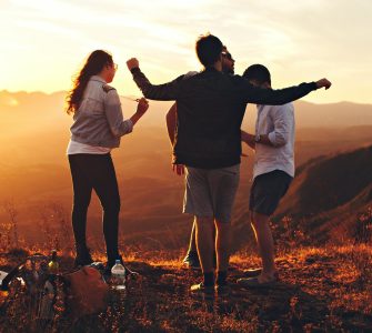 four person standing at top of grassy mountain